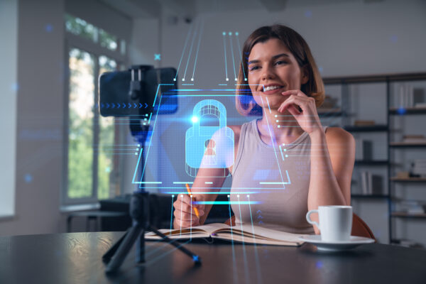 Happy woman is making video blog using smartphone on a tripod explaining with hands at office workplace Concept of online stream, business education, conference call Lock icons hologram