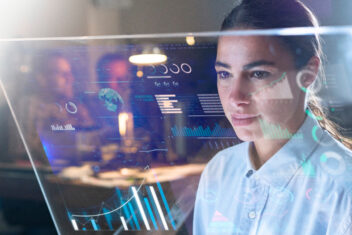 Portrait of a beautiful woman (girl) while she is looking at a futuristic screen with holograms and the office in the background Concept: Future, Technology, work