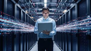 Data Center Chief Technology Officer Holding Laptop, Standing In Warehouse, Information Digitalization Lines Streaming Through Servers SAAS, Cloud Computing, Web Service